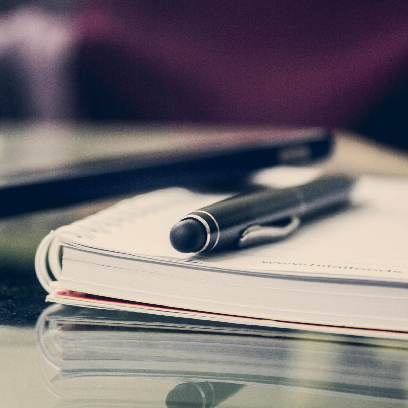 Close-up of an elegant pen resting on an open notebook in a stylish office environment.